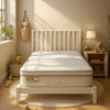 An Eco Kids Deluxe King SIngle Pillow Top Mattress pictured on a white timber bed frame with a slatted bedhead in a child bedroom setting with a teddy bear on a timber bedside table and a toy giraffe in a basket