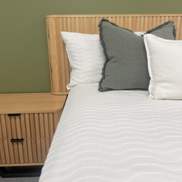 Bedroom setting with an Australis Messmate hardwood timber bed and wooden nightstand featuring pillows in front of a green wall at the Best in Beds Warrawong NSW store