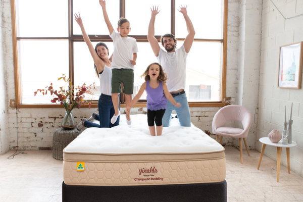 Family jumping on a Yinahla Visco Flex Mattress & Bed Base Ensemble Package. Medium-firm, the solution for sleepers seeking relief for sore spines, joints & aching backs. 20-year warranty.