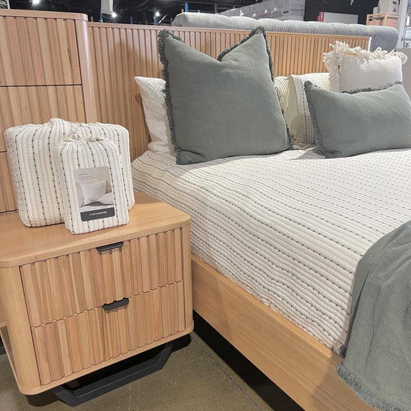 Bedroom setting with an Australis Messmate hardwood timber bed and wooden nightstand featuring pillows and a photo frame at the Best in Beds Campbelltown NSW store
