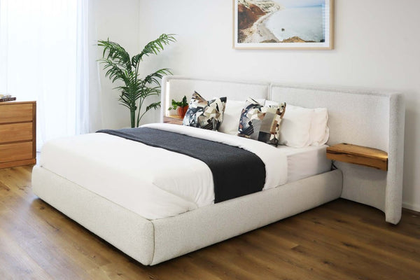 Modern Daintree gas lift storage bed in bedroom with a light grey bed, wooden nightstands, and a framed picture on the wall.