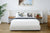 Modern Daintree gas lift storage bed in bedroom with a light grey bed, wooden nightstands, and a framed picture on the wall.