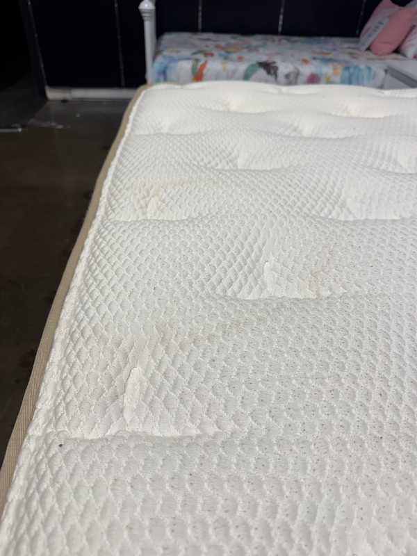 Mattress with visible wear and tear in a bedroom setting