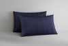 Two navy blue pillows on a light gray surface with a neutral background