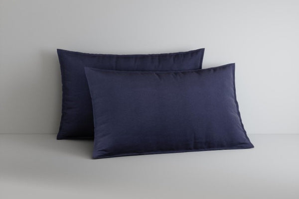 Two navy blue pillows on a light gray surface with a neutral background