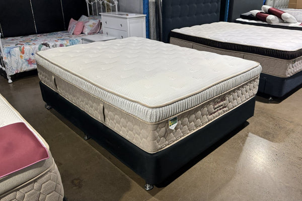 Mattress on display in a showroom with other furniture items.