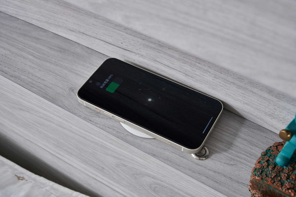 Smartphone charging on the wireless charging pad in the Belleville bedhead bookshelf